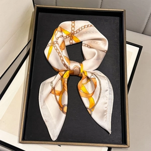 Silk-feel square scarf with gold chain print in orange and cream fold in a bow