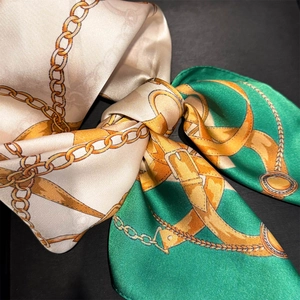 Detailed view of the silk scarf featuring golden chain prints and equestrian horse bits