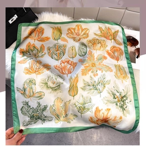 Close-up of elegant floral silk scarf featuring ivory tulips and green borders on plush background