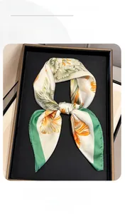 Detail of floral silk scarf with orange flowers and green borders on a black tray