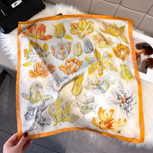 Detailed view of square tulip print silk scarf with vibrant orange border on white faux fur