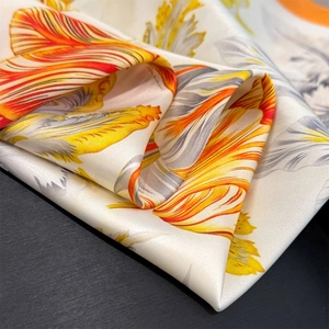 Detail of silk scarf with realistic orange and yellow tulip prints on smooth white fabric