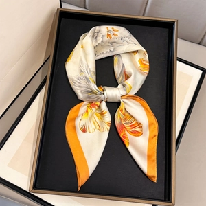 Floral print silk scarf with orange borders on a black tray for a luxury display