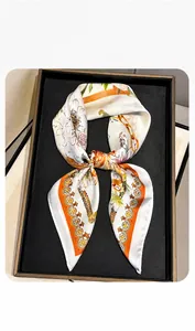 Macro detail of silk scarf with floral print and smooth texture on display tray