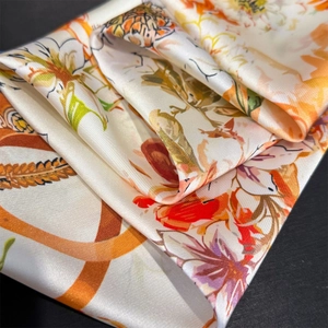 Detailed close-up of premium floral print silk scarf with glossy texture and vibrant colors