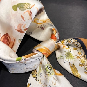 Detail of floral silk scarf showing satin texture with lily and golden chain patterns