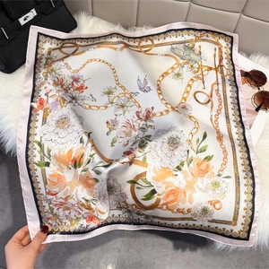 Detail of floral silk scarf with golden chains and vintage patterns on soft white carpet
