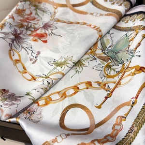 Detailed close-up showing silky texture and elegant floral print with gold chain patterns