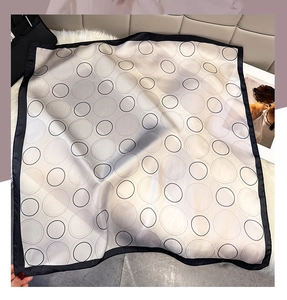 Detail van een zijden vierkante sjaal met geometrische cirkels op een wit bont tapijt