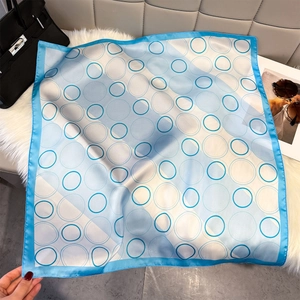 Detail van een zijdeachtige vierkante sjaal met blauw geometrisch cirkelpatroon en rand