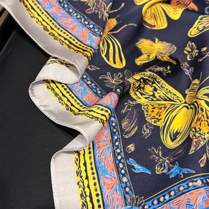 Detailed view of silk-like scarf with butterfly print and satin finish texture