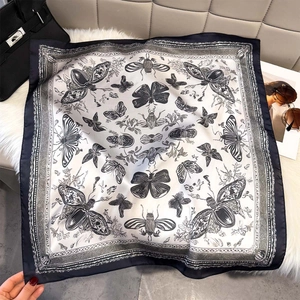 Detailed macro view of the butterfly print on a luxury black and white silk square scarf