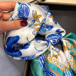 Close-up of luxury silk-like scarf featuring floral butterfly print and vibrant yellow patterns