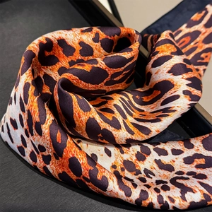 Detailed macro view of leopard print silk scarf texture and elegant fabric draping