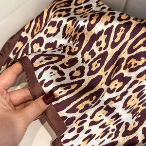 Detail of silk leopard print square scarf featuring brown hem and smooth texture finish
