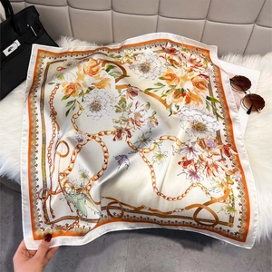 Elegant floral silk scarf with orange border and luxury chain motifs on plush background