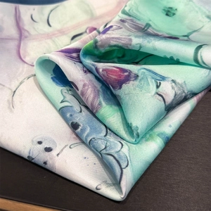 Macro shot of mint green and purple watercolor floral print on silky satin fabric