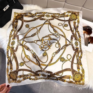 Flat lay of vintage chain print silk scarf with luxury accessories on white plush background
