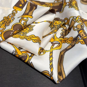 Detail of luxury silk scarf with vintage gold chain and equestrian horsebit print