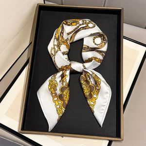 Elegant silk scarf with vintage gold chain and horsebit print on a black display tray