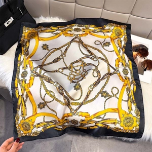 Detail shot of luxury silk scarf with gold chain and floral baroque pattern on a bag