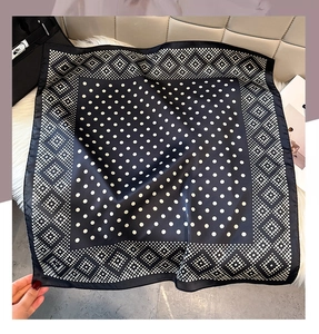 Detailed view of black and white polka dot scarf tied elegantly to a designer handbag