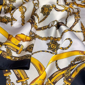Detail of luxury silk scarf with chain print and glossy satin texture in yellow and white