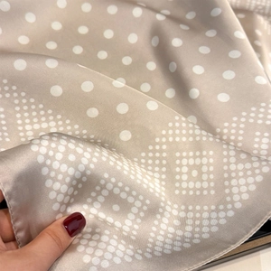 Detailed view of the smooth champagne silk scarf with geometric polka dot pattern texture