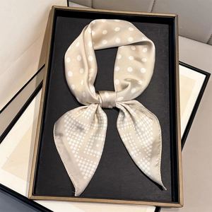 Detail of champagne gold silk scarf with white polka dots tied in an elegant knot