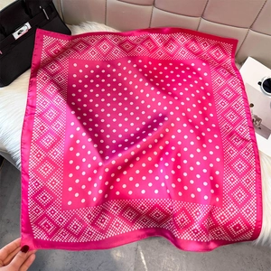 Detailed view of magenta polka dot silk scarf draped on soft textured background