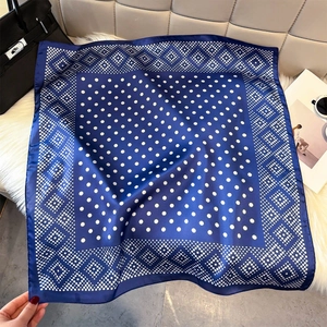 Detail of navy blue silk-like square scarf with white polka dots on soft faux fur