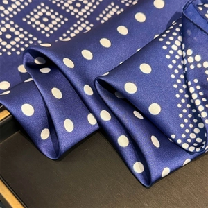 Detail view of the navy blue satin scarf featuring classic white polka dot patterns