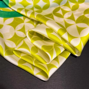 Detailed view of light green geometric silk scarf with glossy satin texture and fine edges