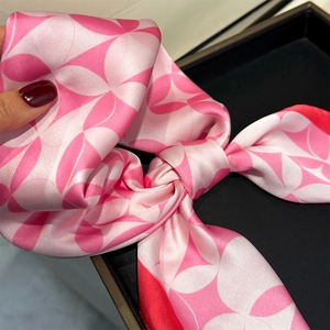 Close-up of pink geometric floral silk scarf tied in a bow with red border details