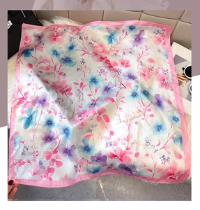 Close-up of square satin scarf with pink and blue floral prints on faux fur mat