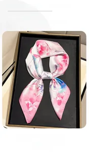 Detailed macro view of floral print silk scarf with satin finish on a black tray