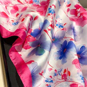 Detailed view of floral silk scarf featuring pink and blue flowers with magenta borders