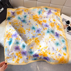 Detail of floral silk square scarf with blue and yellow prints on white fur background