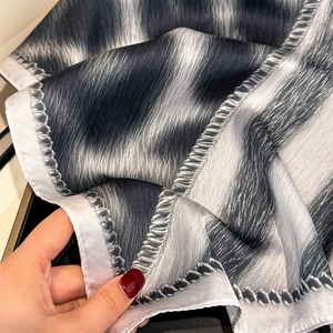 Detailed close-up showing the silk-like texture and fine hem stitching of this scarf