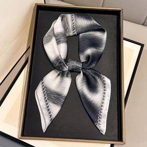 Elegant leopard and stripe print silk scarf tied in a bow on a black display tray