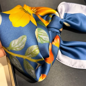 Dettaglio della sciarpa in seta a fiori blu pavone con elegante bordo arrotolato bianco