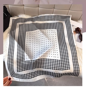 Macro view of silky square scarf with classic black and white houndstooth pattern details