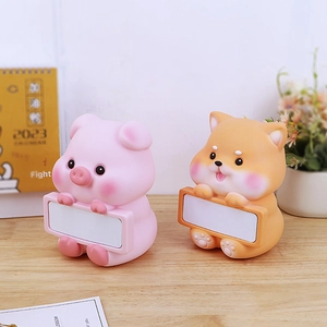 Macro detail of cartoon pig and dog figurines with white message boards on wooden desk