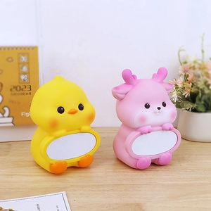 Detail of yellow chick and pink deer cartoon piggy banks on a wooden desk setup