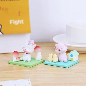 Close-up of resin animal figurines including a white unicorn and pink pig on desk