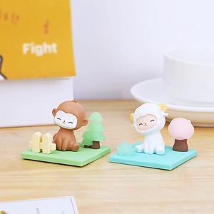 Detailed view of monkey and sheep figurines on a wooden desk with a bright background