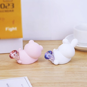Detail of cute resin pig and rabbit night lights on a warm wooden office desk setup