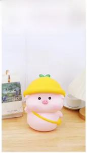 Detail of pink pig piggy bank with yellow hat on a cozy wooden desk with decor