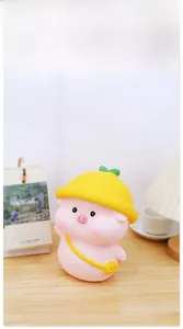 Close-up of pink pig money box with yellow hat on a wooden desk in a cozy room