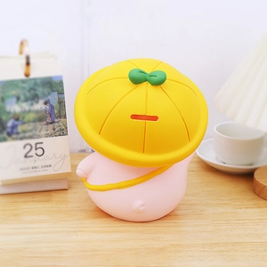 Cute pink pig piggy bank with a yellow sprout hat on a warm wooden home desk